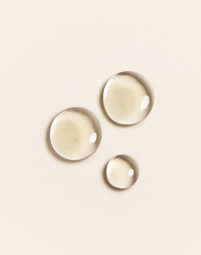 Three clear water droplets on a beige background.
